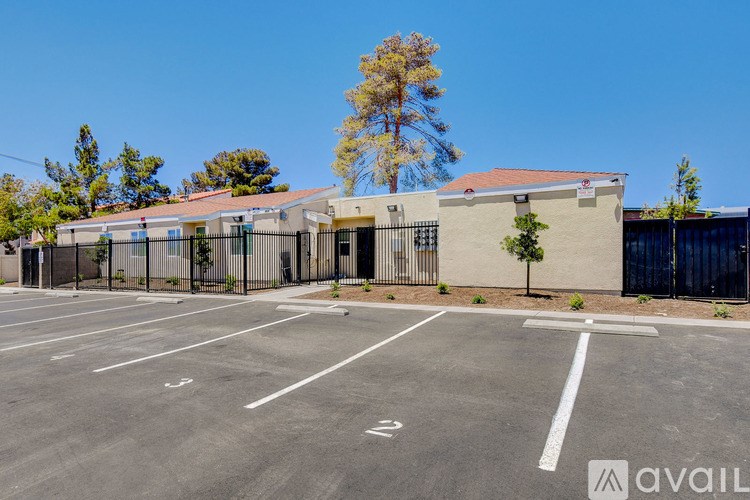 A parking lot with a building and trees in the background.