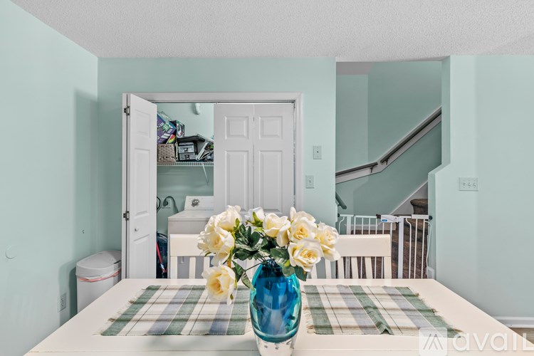 A vase of white flowers sits on a table in a room with light blue walls.