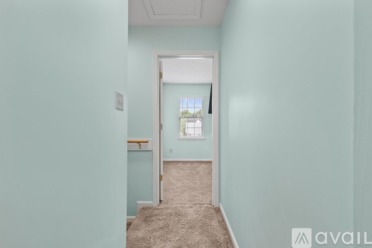 A hallway with a carpeted floor and a doorway leading to another room.