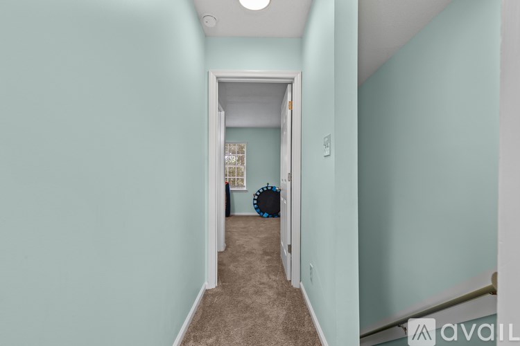 A hallway with a carpeted floor and a door at the end.