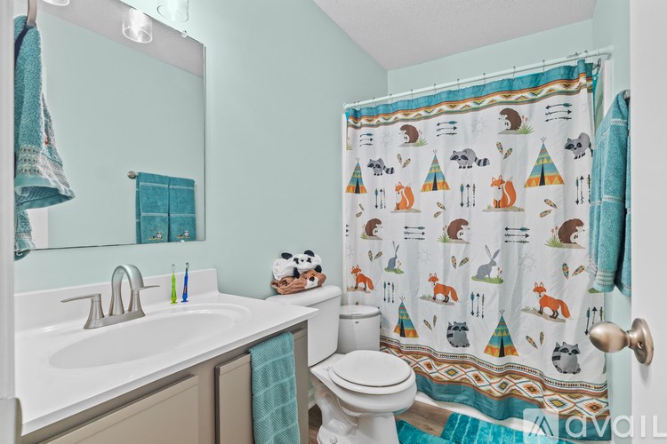 A bathroom with a white toilet, a sink with a mirror above it, and a shower curtain with animal designs.