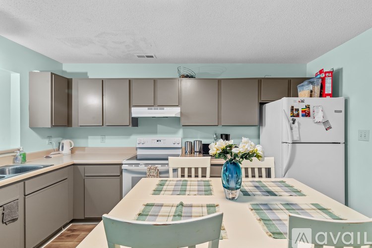 A kitchen with a table set for four with a vase of flowers on it.