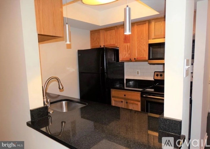 A kitchen with black appliances and wooden cabinets.