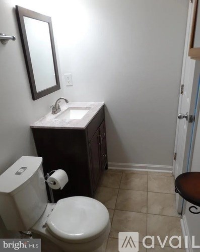 A bathroom with a toilet, sink, and mirror.
