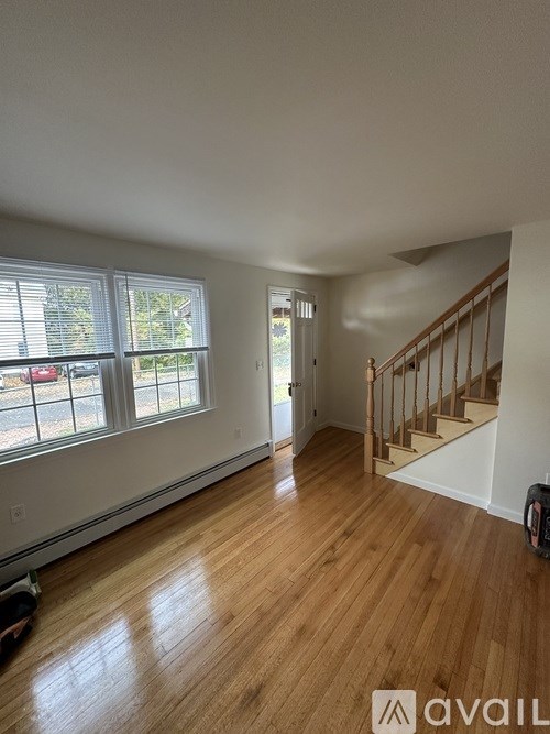 A room with wooden floors and a staircase leading to another room.