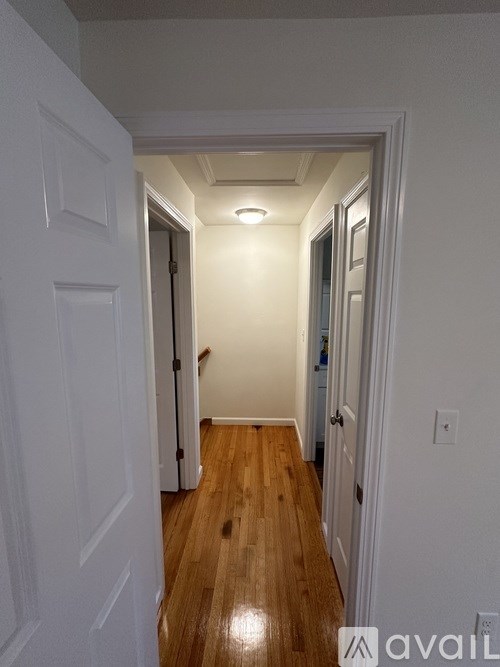 A hallway with white walls and wooden floors.