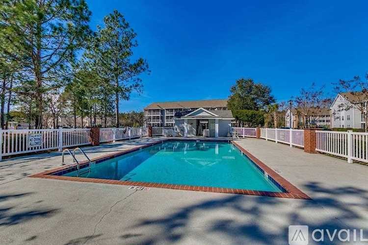A swimming pool surrounded by a white fence and trees.