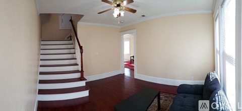 A living room with a staircase and a ceiling fan.
