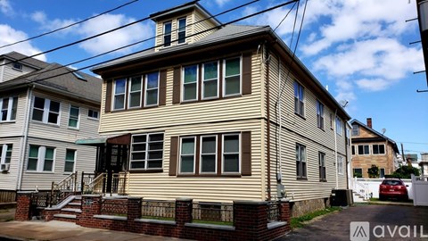 A house with a beige siding and a red car parked in front.