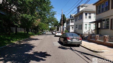 A car is parked on a residential street lined with houses.