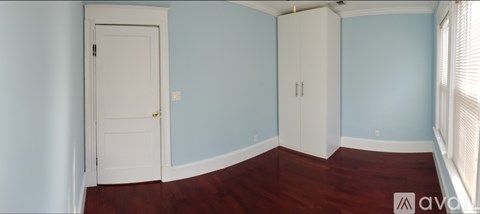 A room with a white door and a wooden floor.