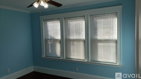 A room with a ceiling fan and two windows with blinds.