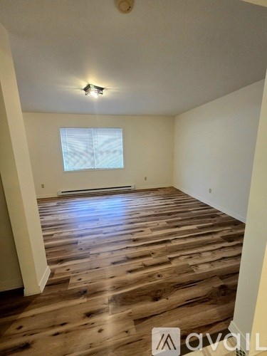 A room with wooden flooring and a window with blinds.