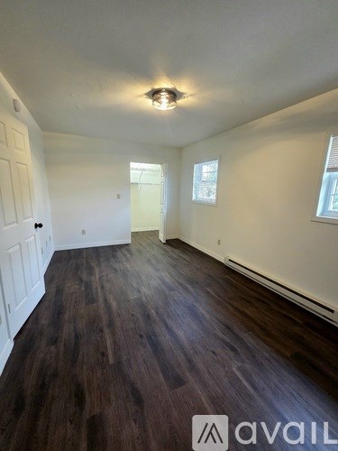 A room with wooden flooring and white walls.