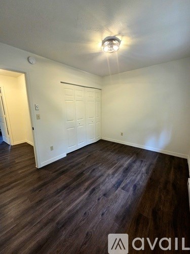 A room with a white door and wooden flooring.