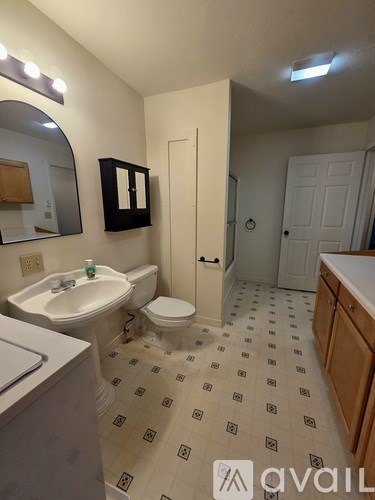 A bathroom with a white sink, toilet, and tiled floor.