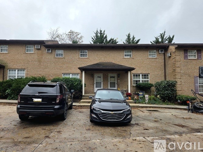 Two cars are parked in front of a brick apartment building.