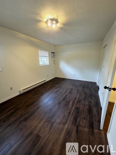 A room with wooden flooring and a window.