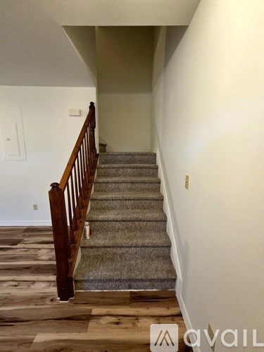A staircase with a wooden railing and a carpeted runner.