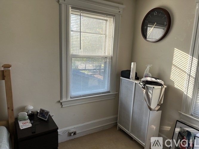 A room with a window, a clock, and a cabinet.
