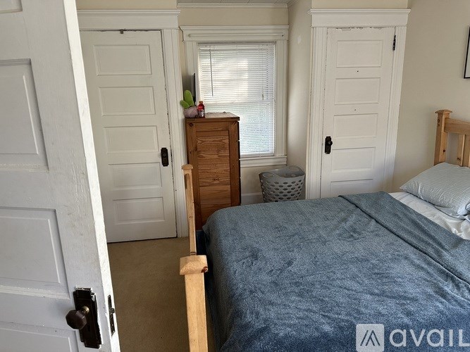 A bedroom with a bed, dresser, and two doors.