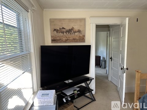 A living room with a flat screen TV mounted on the wall and a painting of a horse above it.