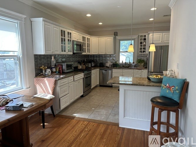 A kitchen with white cabinets and a wooden floor.