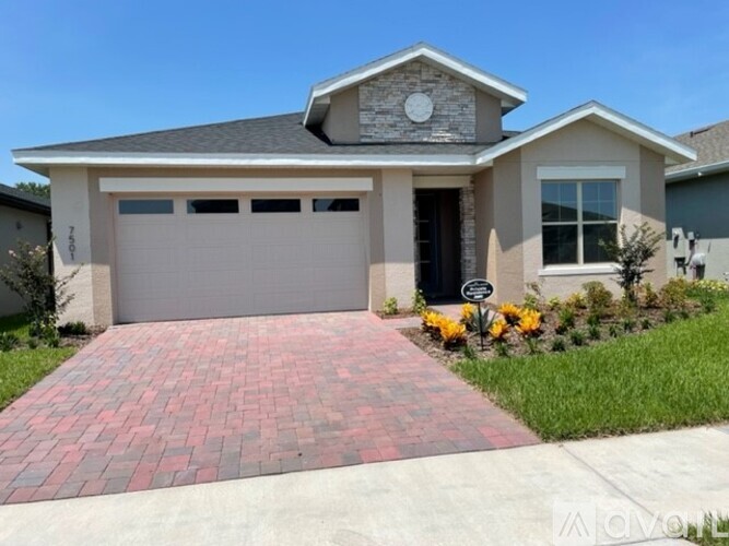 A house with a grey garage door and a brick pathway leading to it.