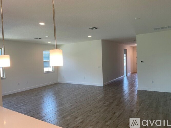 A spacious room with wooden flooring and a large window.
