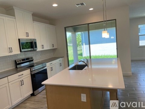 A kitchen with white cabinets and a large island in the middle.