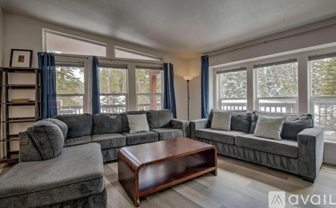 A living room with grey couches and a wooden coffee table.