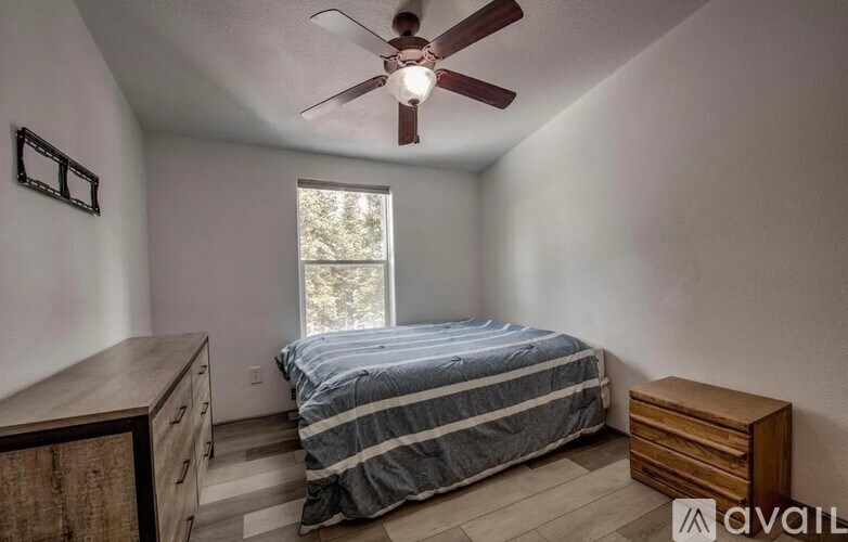 A bedroom with a bed, dresser, and window.