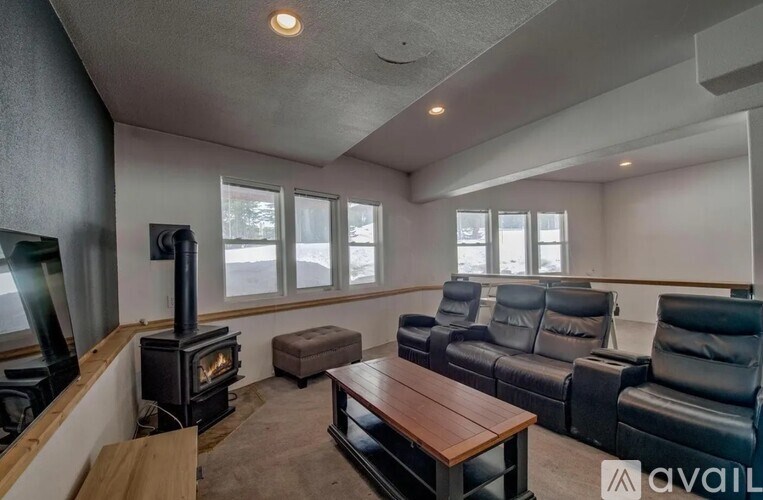 A living room with a wood stove and black leather couches.