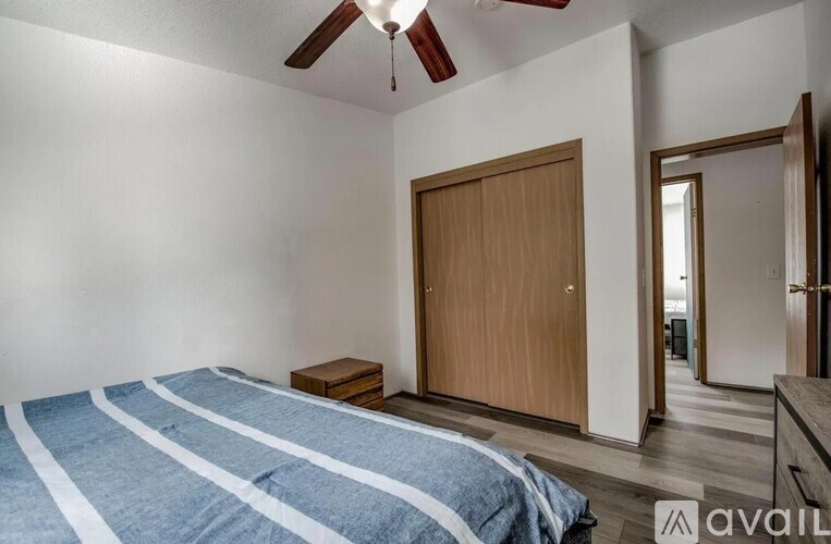 A bedroom with a bed, a ceiling fan, and a wooden door.