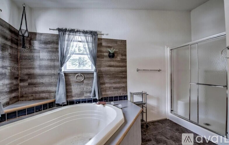 A bathroom with a tub, a window, and a shower.