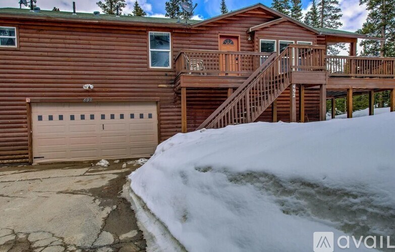 A brown wooden house with a snow-covered ground in front.