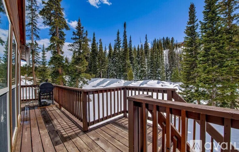 A wooden deck with a chair and a mountain in the background.