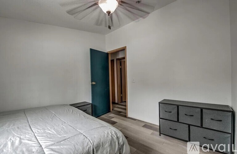 A bedroom with a bed, dresser, and a door.