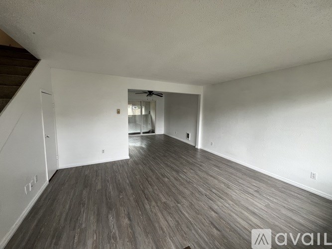 A spacious room with wooden flooring and white walls.