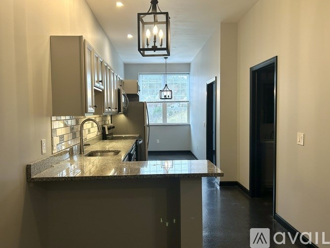 A modern kitchen with a granite countertop and a hanging light fixture.