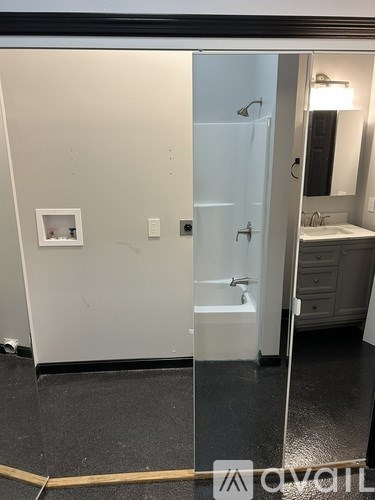 A bathroom with a white door and a mirror.