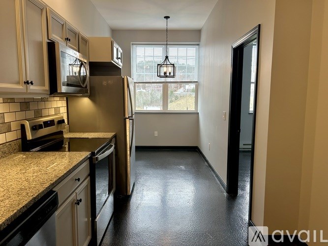 A kitchen with black countertops and a refrigerator.
