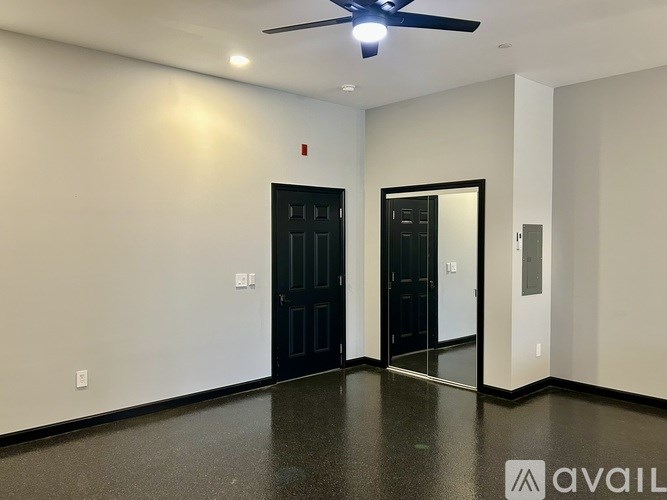 A room with a ceiling fan and two doors.