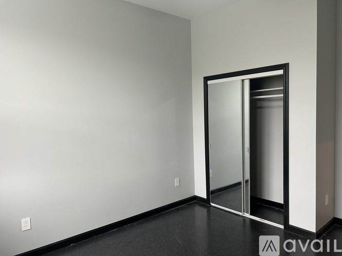 A room with a mirrored door and a light switch on the wall.
