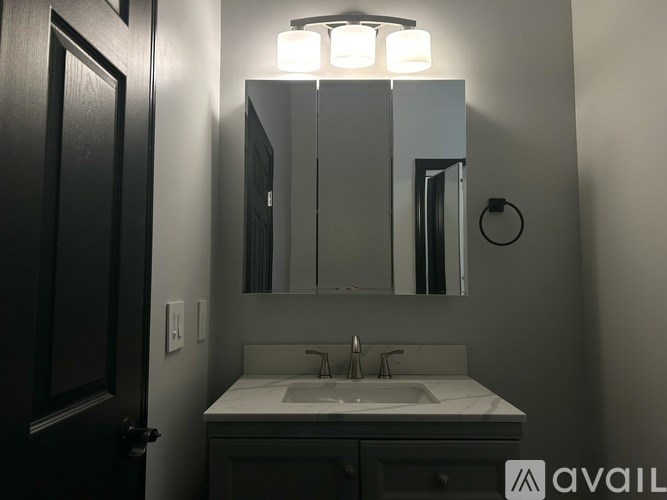 A bathroom with a sink, mirror, and light fixture.