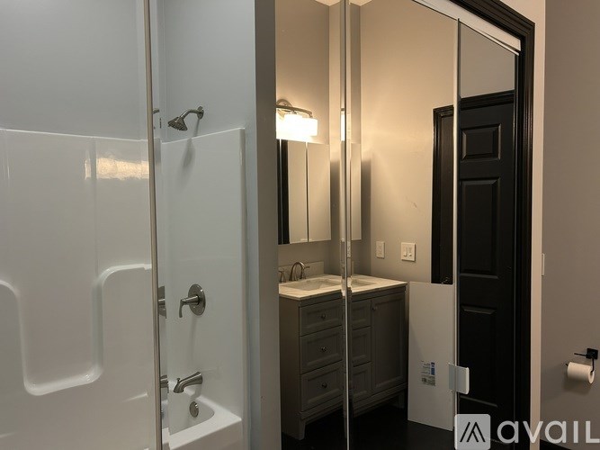 A bathroom with a white shower and a sink with a mirror above it.
