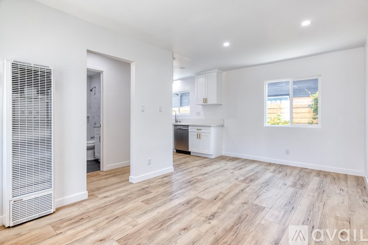 A spacious, empty room with wooden flooring and white walls.