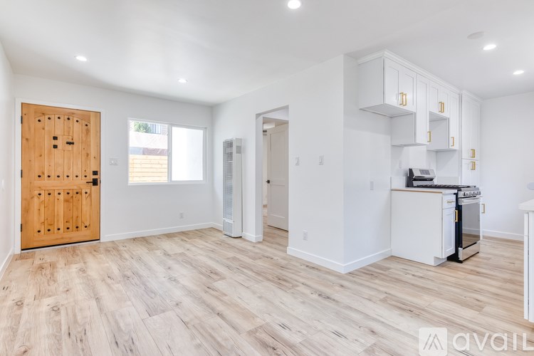 A kitchen area with a wooden door, white cabinets, and a white dishwasher.