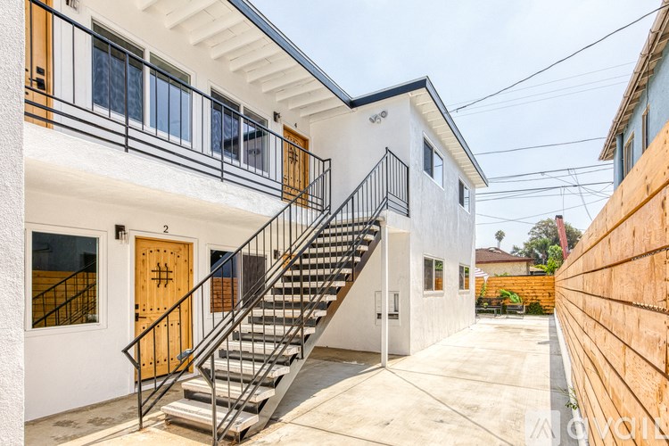 A white house with a black metal staircase.