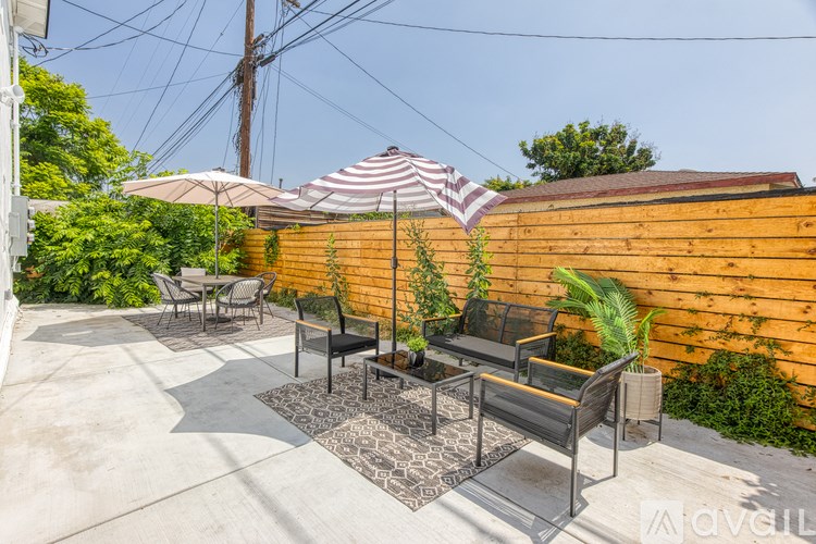 A patio with a striped umbrella and a wooden wall.